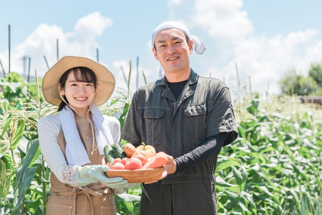 収穫した野菜を持つ農夫と女性